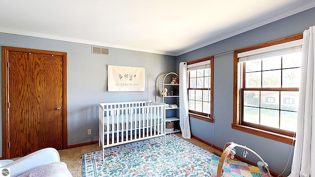 carpeted bedroom with ornamental molding and a crib