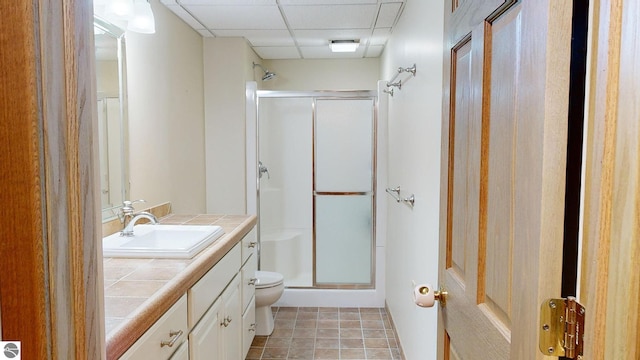 bathroom with vanity, a drop ceiling, a shower with shower door, and toilet