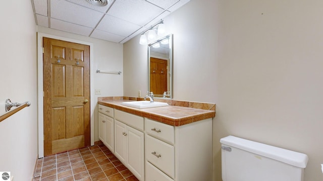 bathroom featuring toilet, a drop ceiling, vanity, and tile patterned flooring