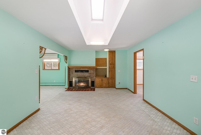 carpeted living room featuring a baseboard radiator, a stone fireplace, and a skylight