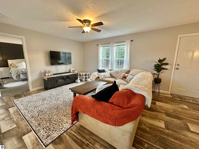 living room with ceiling fan, hardwood / wood-style flooring, and a textured ceiling