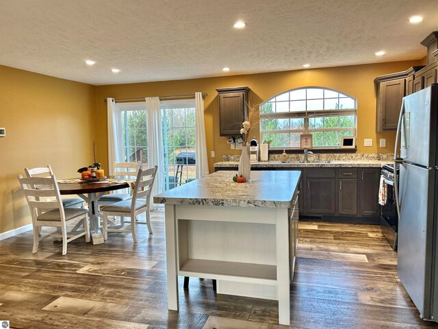 kitchen with a textured ceiling, a healthy amount of sunlight, stainless steel appliances, and dark hardwood / wood-style flooring