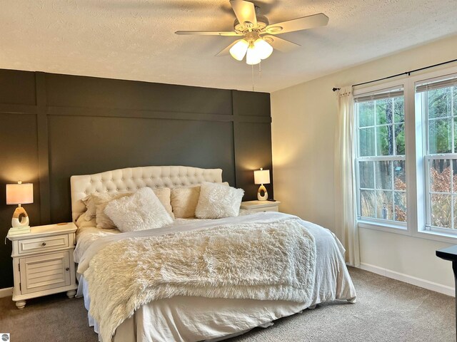 carpeted bedroom with ceiling fan and a textured ceiling