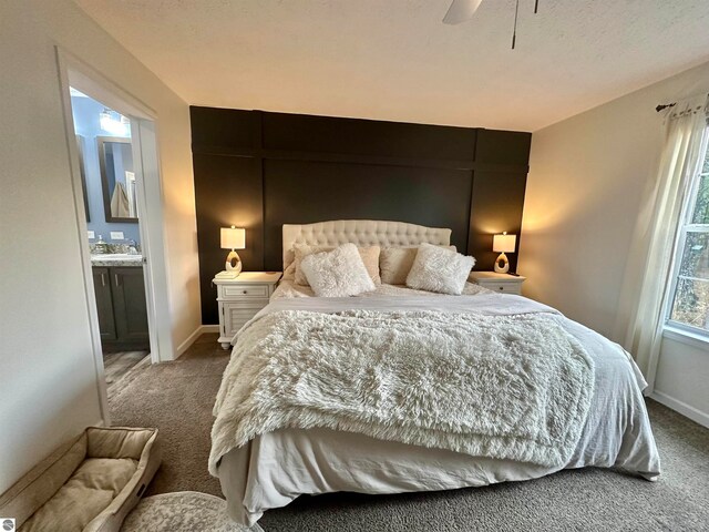 bedroom with connected bathroom, sink, carpet floors, and ceiling fan