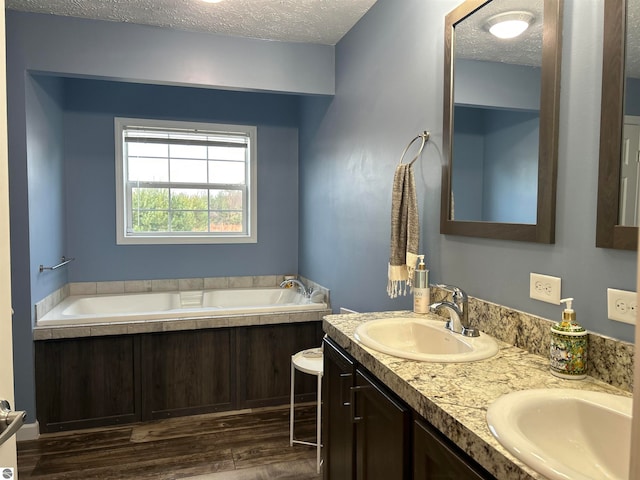 bathroom featuring vanity, a tub, hardwood / wood-style flooring, and a textured ceiling