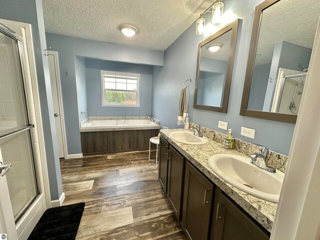 bathroom with vanity, independent shower and bath, a textured ceiling, and wood-type flooring