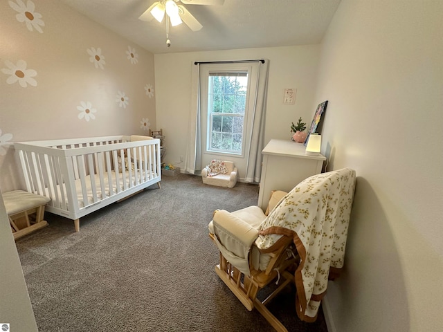 bedroom with dark carpet, a crib, and ceiling fan