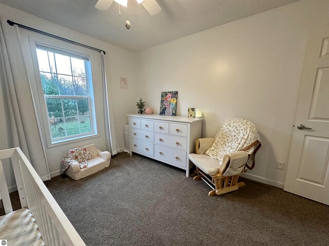 living area featuring ceiling fan and dark colored carpet