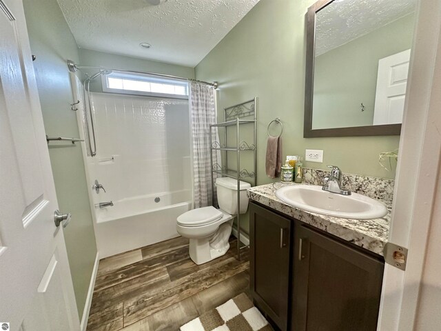 full bathroom featuring shower / tub combo, a textured ceiling, hardwood / wood-style floors, toilet, and vanity