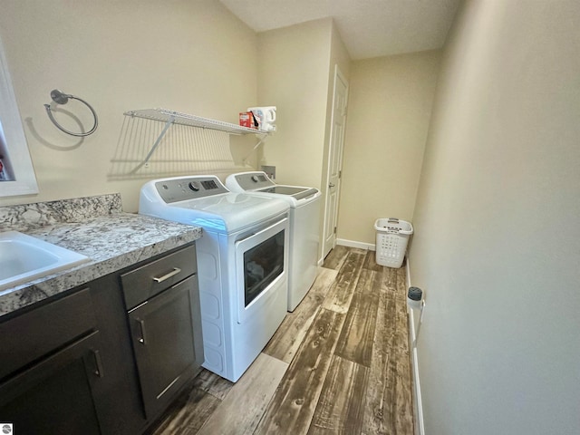 laundry area with sink, independent washer and dryer, dark hardwood / wood-style floors, and cabinets