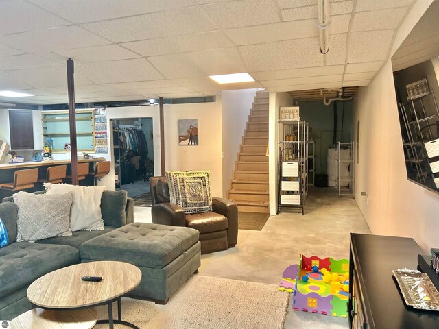 living room with a paneled ceiling and concrete flooring