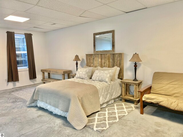 bedroom with a drop ceiling and concrete floors