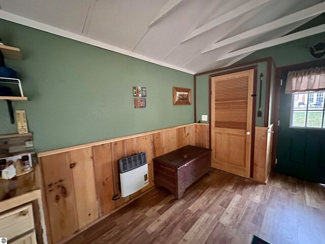 interior space featuring heating unit, wood-type flooring, lofted ceiling, and wooden walls