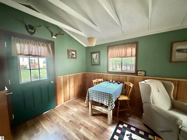 dining room featuring a wealth of natural light, hardwood / wood-style floors, vaulted ceiling, and wood walls