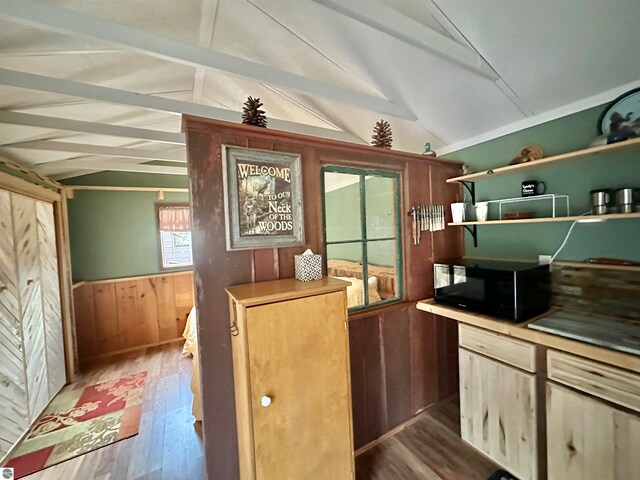 kitchen featuring dark wood-type flooring, lofted ceiling with beams, and wood walls