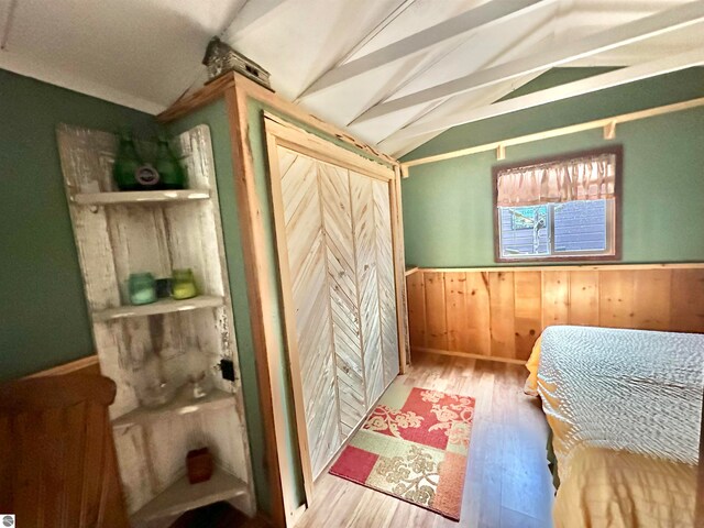 bedroom featuring vaulted ceiling, wood-type flooring, and wood walls