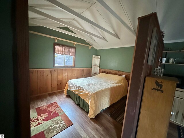 bedroom featuring vaulted ceiling, hardwood / wood-style flooring, and wood walls