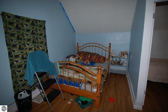 bedroom with dark wood-type flooring and lofted ceiling