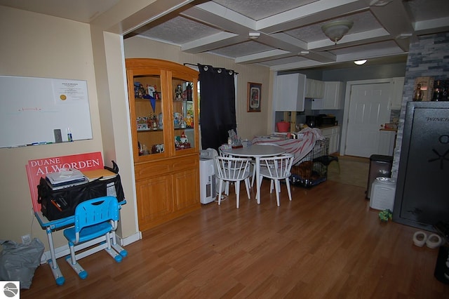 dining area featuring beam ceiling, coffered ceiling, and light hardwood / wood-style floors