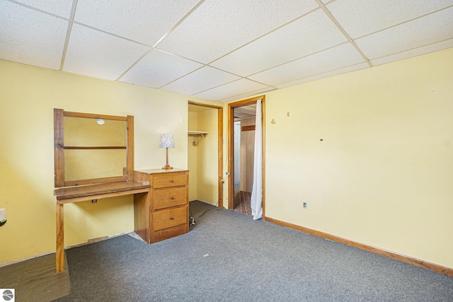 interior space featuring a paneled ceiling and dark carpet