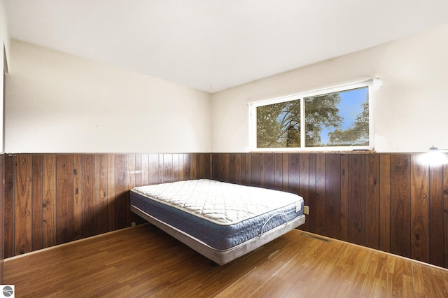 bedroom featuring hardwood / wood-style floors and wood walls