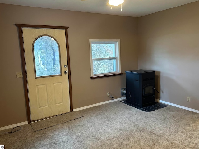 carpeted foyer featuring a wood stove and ceiling fan