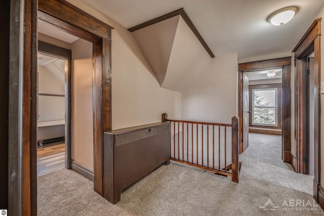 hall with carpet floors and an upstairs landing