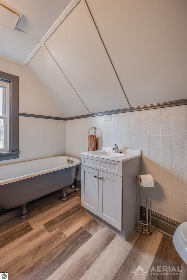 bathroom with vanity, lofted ceiling, wood finished floors, and a freestanding bath