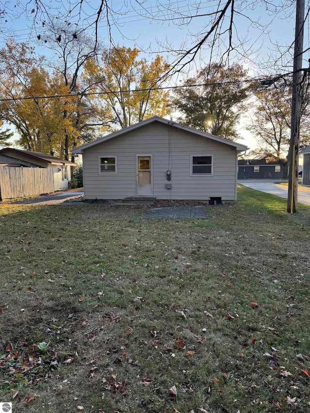 back house at dusk featuring a yard