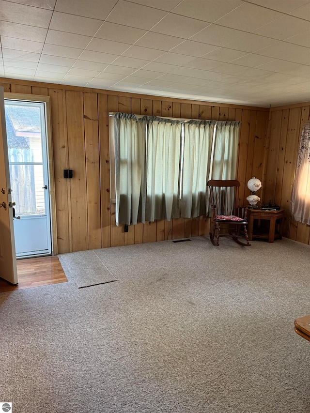 carpeted foyer entrance with wood walls