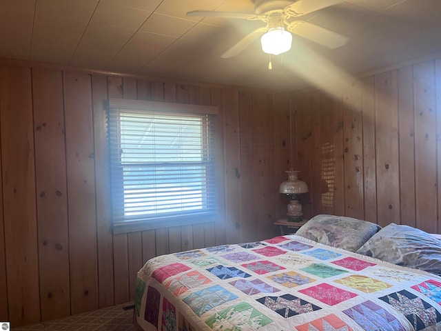 bedroom featuring ceiling fan and wood walls