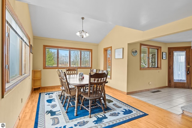 dining room with light hardwood / wood-style floors, a notable chandelier, french doors, and vaulted ceiling