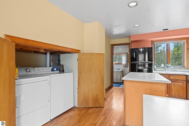 kitchen with sink, washer and clothes dryer, light hardwood / wood-style floors, and black fridge