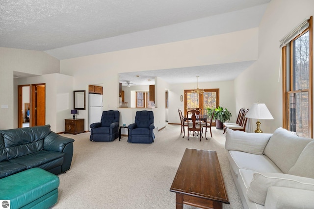 carpeted living room featuring a textured ceiling, ceiling fan with notable chandelier, and lofted ceiling