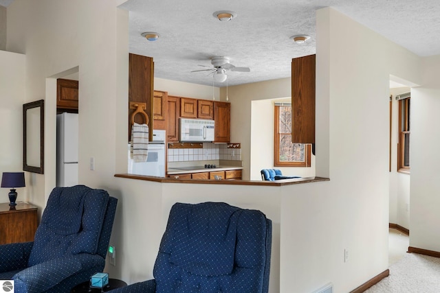 kitchen featuring white appliances, ceiling fan, decorative backsplash, light colored carpet, and kitchen peninsula