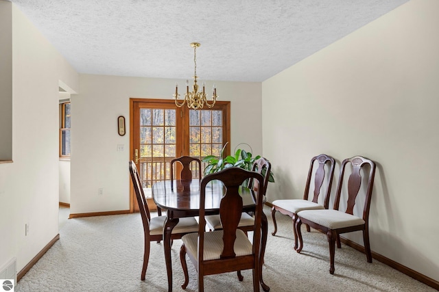 dining area with light colored carpet, a textured ceiling, and a chandelier