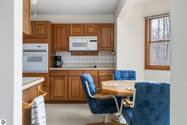 kitchen with a textured ceiling, white appliances, and tasteful backsplash