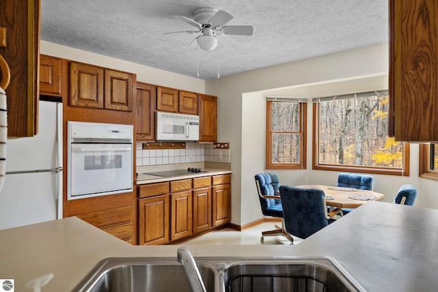 kitchen featuring a textured ceiling, decorative backsplash, ceiling fan, and white appliances