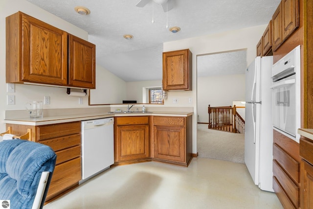 kitchen featuring kitchen peninsula, white appliances, light colored carpet, ceiling fan, and sink