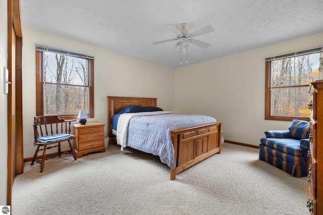 carpeted bedroom with ceiling fan and a textured ceiling