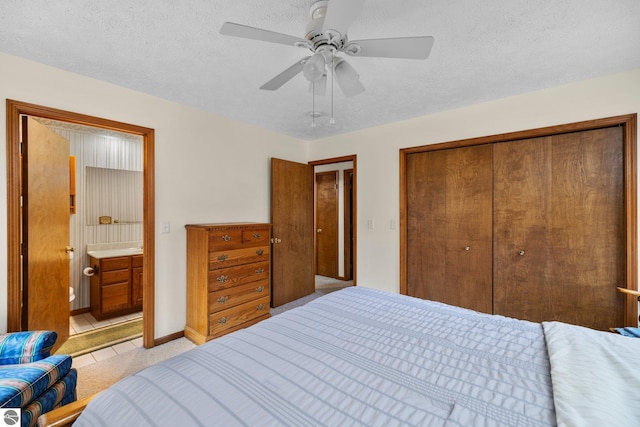 carpeted bedroom with ensuite bathroom, ceiling fan, a textured ceiling, and a closet