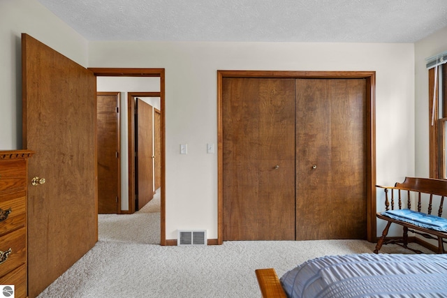 carpeted bedroom with a closet and a textured ceiling