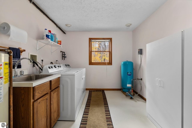 washroom featuring cabinets, gas water heater, sink, washer and dryer, and a textured ceiling