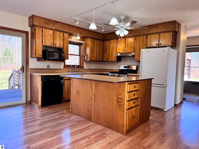 kitchen with black appliances, a kitchen island, light wood-type flooring, and sink