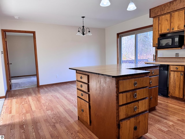 kitchen with light wood-type flooring, black appliances, an inviting chandelier, a center island, and hanging light fixtures