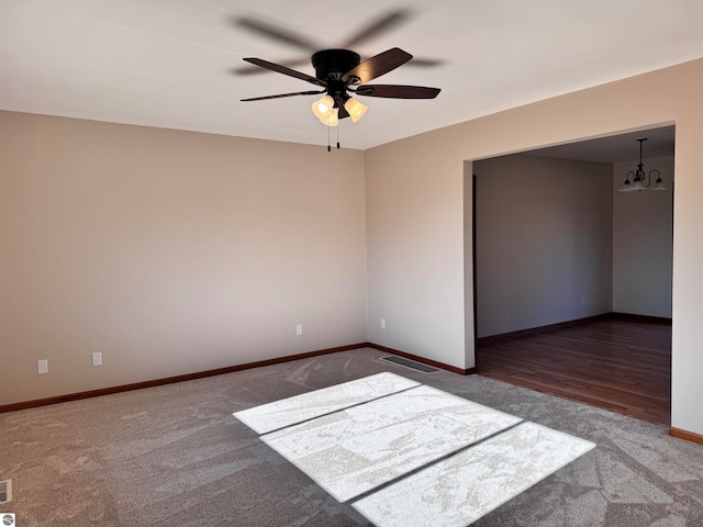 spare room with hardwood / wood-style floors and ceiling fan with notable chandelier