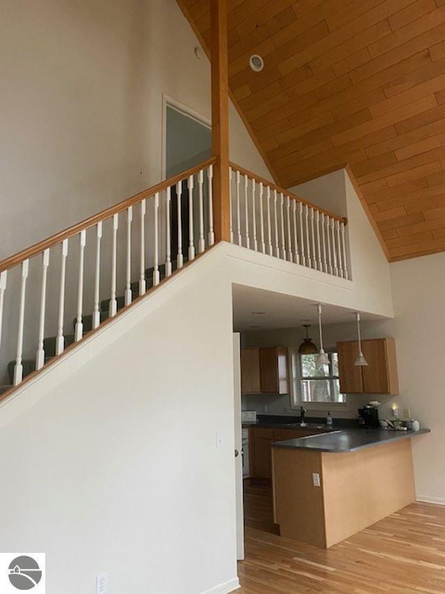 4709 State Park Hwy, Interlochen, MI 49643 - kitchen with high vaulted ceiling, dark countertops, a peninsula, wood finished floors, and wooden ceiling