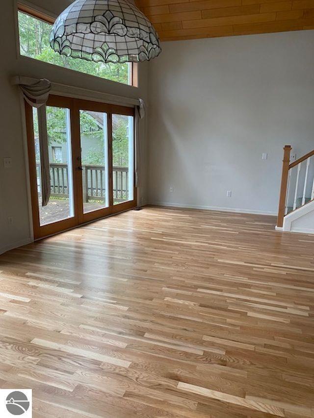 4709 State Park Hwy, Interlochen, MI 49643 - unfurnished living room featuring light wood finished floors, baseboards, and high vaulted ceiling