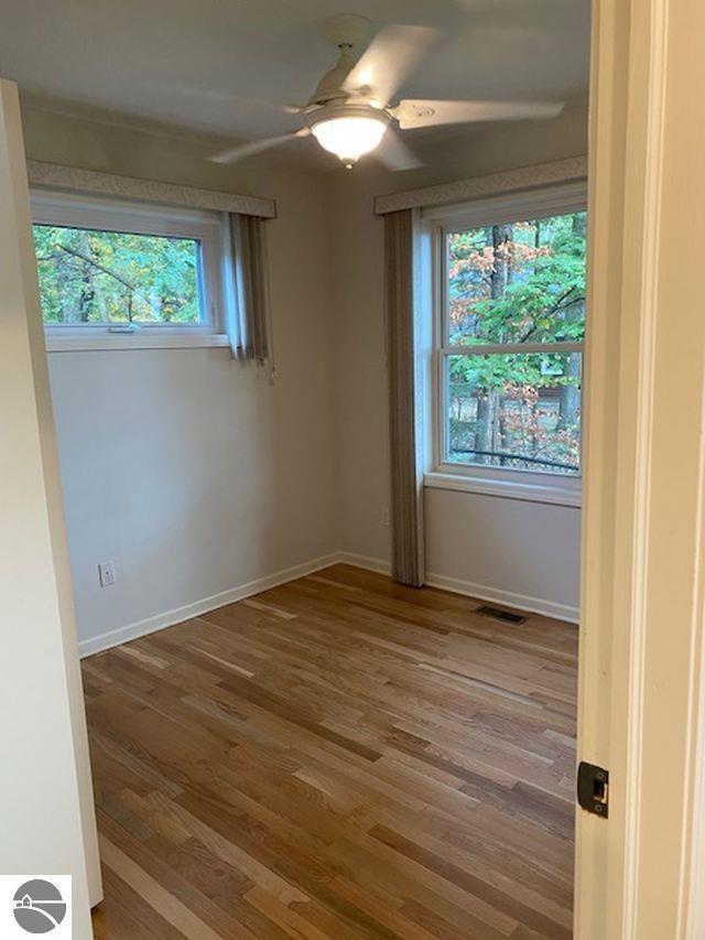 4709 State Park Hwy, Interlochen, MI 49643 - unfurnished room with wood finished floors, a ceiling fan, and baseboards