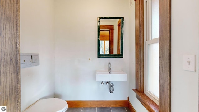 bathroom with toilet, a healthy amount of sunlight, sink, and tile patterned flooring